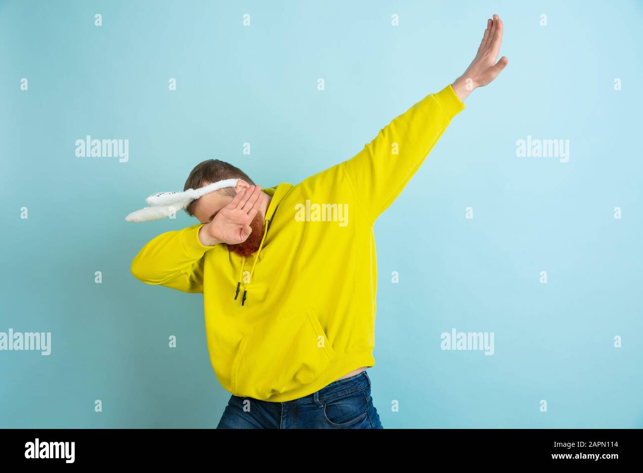 Création de dab. Homme caucasien comme lapin de Pâques avec des vêtements décontractés lumineux sur fond bleu studio. Joyeuses salutations de pâques. Concept d'émotions humaines, d'expression faciale, de vacances. Copyspace. Banque D'Images
