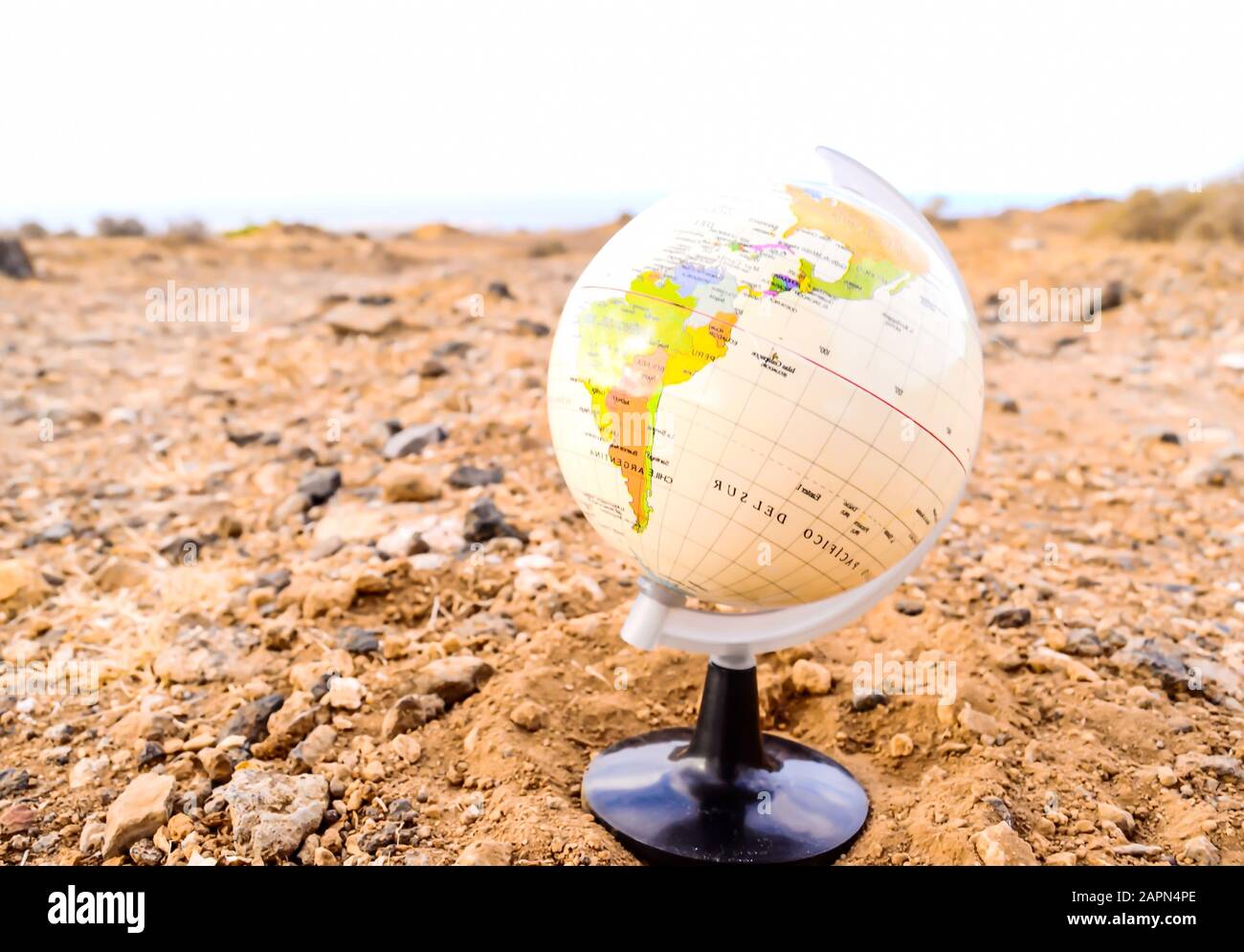 Gros plan d'un modèle de globe 3D couleur pêche sur un surface rocheuse avec un arrière-plan flou Banque D'Images