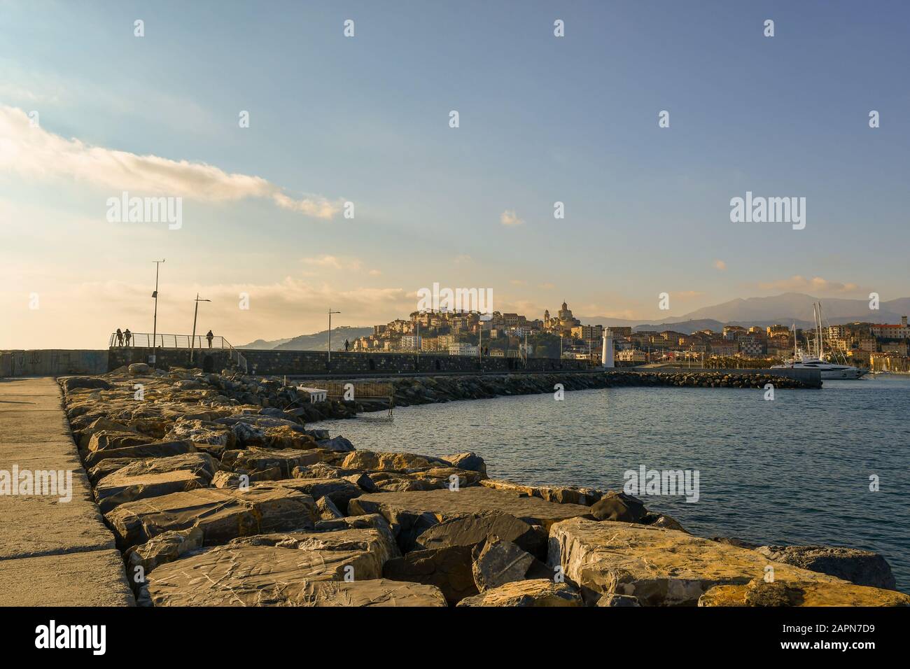 Vue panoramique depuis un brise-lames rocheux de la ville côtière de Porto Maurizio avec le port, le phare et les gens marchant, Imperia, Ligurie, Italie Banque D'Images