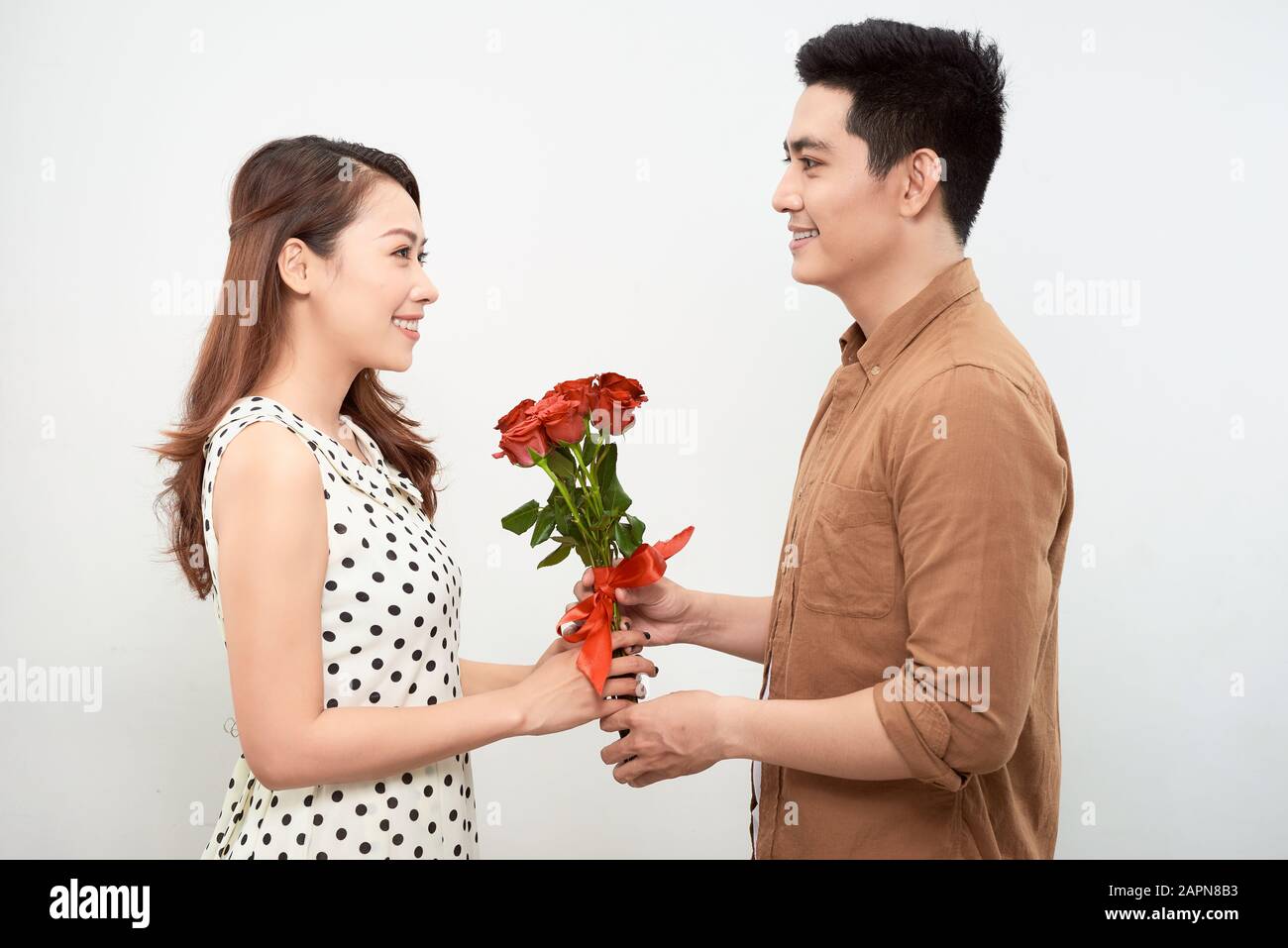 Tout mon amour pour vous. Gros plan portrait de beau jeune couple tenant bouquet de roses et souriant tout en regardant l'un sur l'autre tout en étant isolé sur wh Banque D'Images