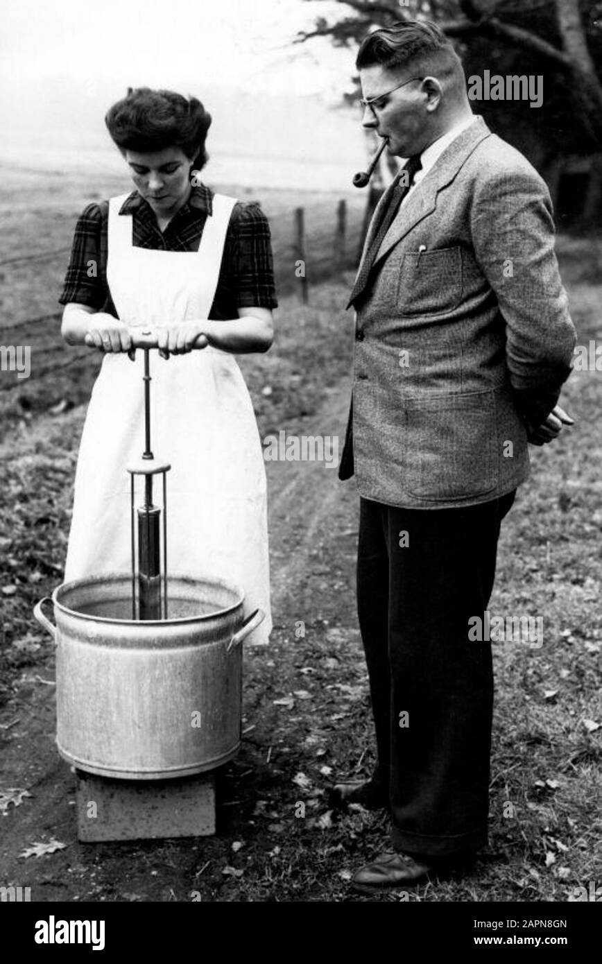 Inventor E. Koer a inventé un appareil, avec lequel un lavage peut être fait en cinq minutes. L'utilisation de cette solution coûte moins de savon et moins d'effort. Le cours et sa femme montrent à l'extérieur sur l'herbe ce premier lave-linge à pompe". Avec cette machine, qui ressemble à un teil avec une pompe à vélo, l'eau savonneuse est battue à travers la cire au lieu de l'inverse habituel. 'T Joppe, Gorsel, 30 Janvier 1951. Banque D'Images