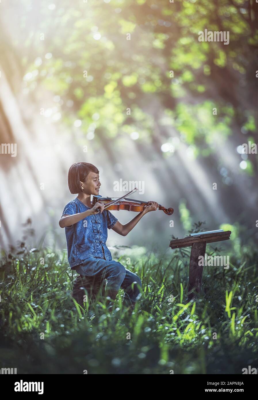 Petit enfant asiatique jouant au violon à l'extérieur Banque D'Images