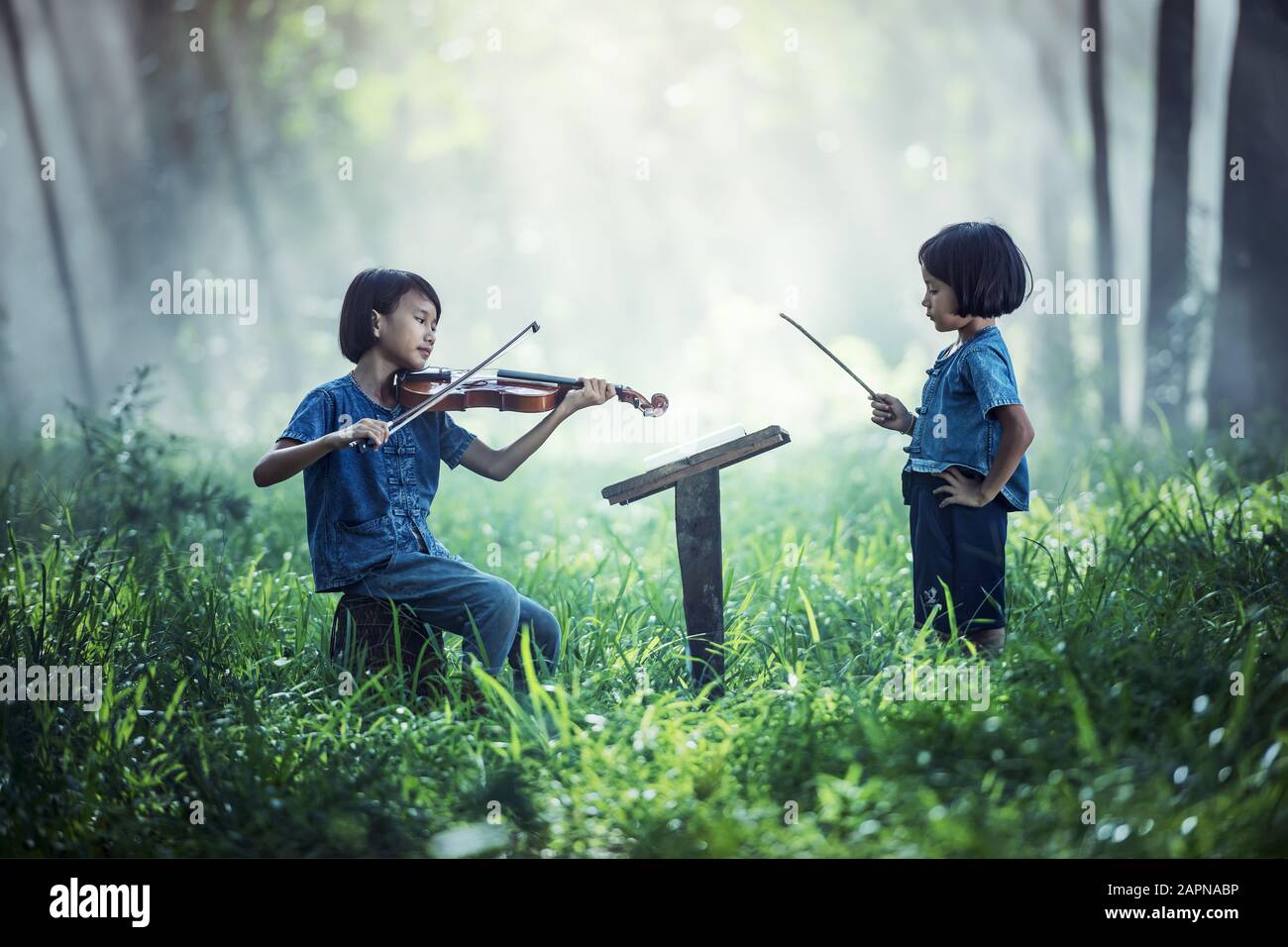 Petit enfant asiatique jouant au violon à l'extérieur Banque D'Images