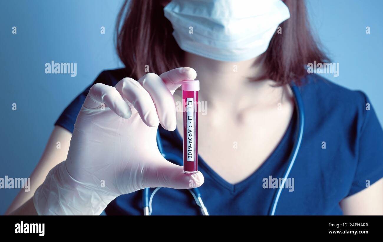 Masque respiratoire portant le masque de protection respiratoire tenant dans le tube de test manuel avec du sang du patient pour l'analyse biochimique 2019-nCoV. Éclosion du virus chinois Wuhan. Coronavir Banque D'Images