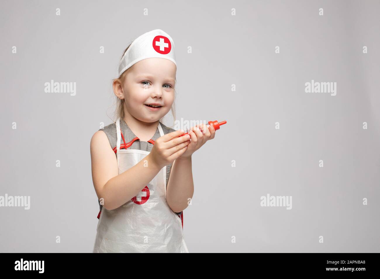 Petite jolie fille drôle jouant portant l'uniforme de médecin tenant seringue  jouet regardant l'appareil photo Photo Stock - Alamy