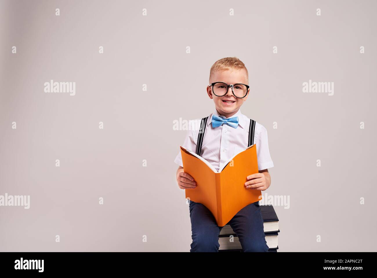Un écolier souriant qui lit un livre Banque D'Images
