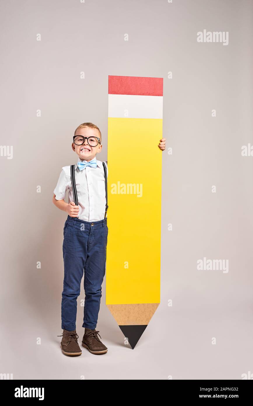 Un garçon souriant tenant un gros crayon Banque D'Images