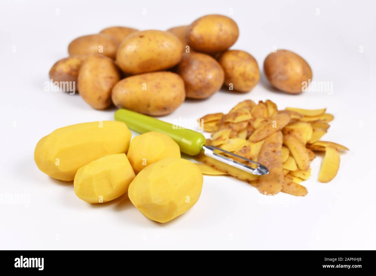 Préparation de la nourriture avec potatos pelés, peels et pommes de terre entières en arrière-plan Banque D'Images