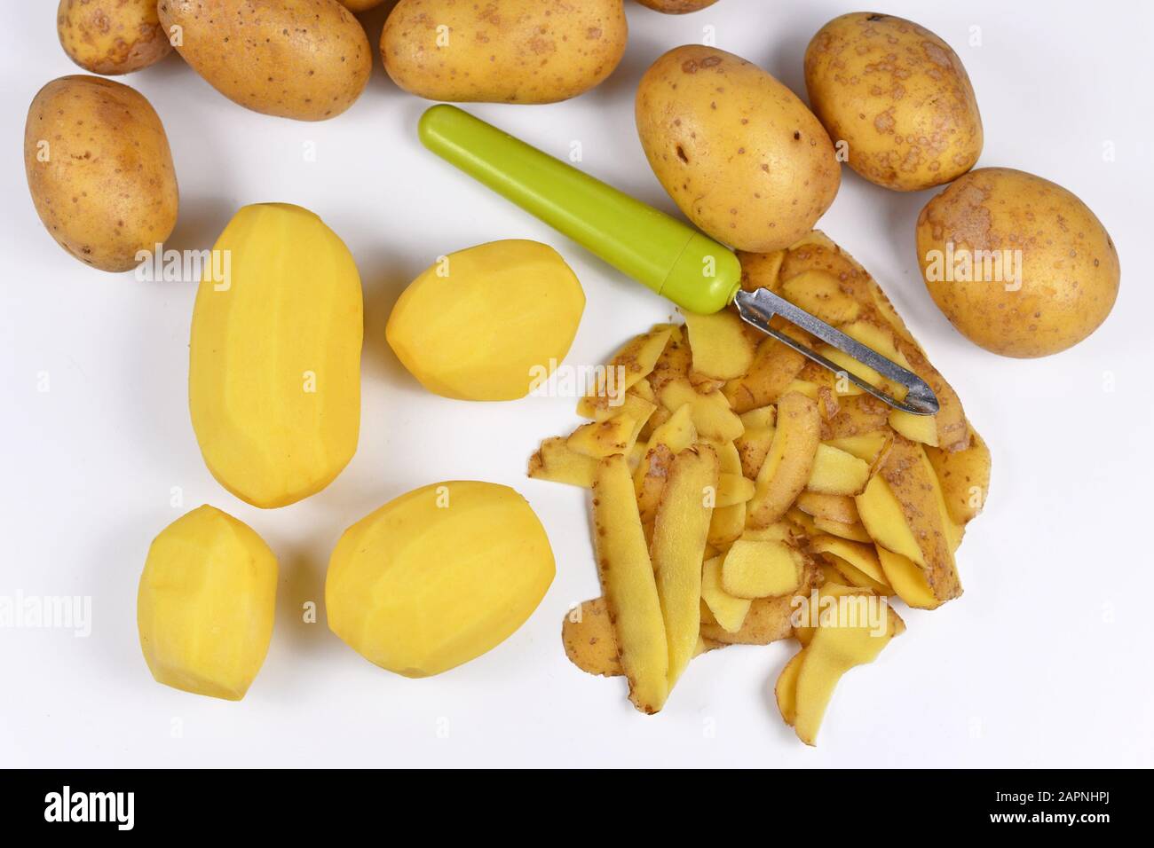 Préparation de la nourriture avec potatos pelés, peels et pommes de terre entières en arrière-plan Banque D'Images