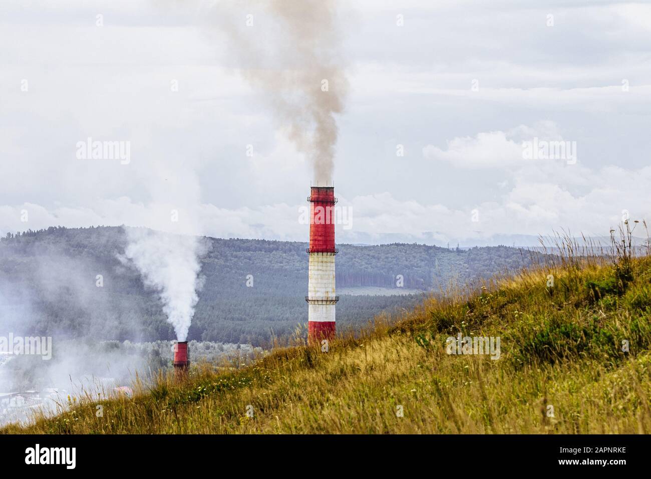 concept de pollution environnementale. tuyaux avec fumée sur fond de forêt et de montagne Banque D'Images