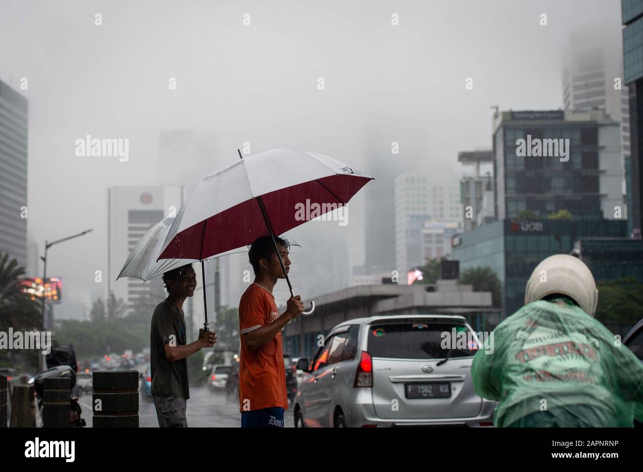 (200124) -- JAKARTA, le 24 janvier 2020 (Xinhua) -- Les Gens avec des parasols se tiennent sur le côté d'une rue car le brouillard couvre les bâtiments le long de la rue principale à Jakarta, Indonésie, le 24 janvier 2020. (Xinhua/Veri Sanovri) Banque D'Images