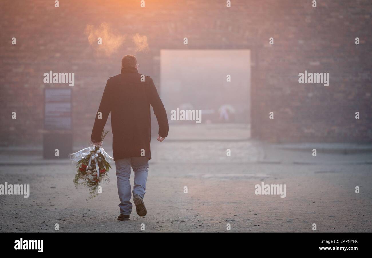 24 janvier 2020, Pologne, Oswiecim: Tôt le matin, un homme pose des fleurs sur le mur noir dans la cour entre Les Blocs 10 et 11 de l'ancien camp de concentration d'Auschwitz I. Des fusillades ont eu lieu au mur noir jusqu'en décembre 1943. 27.01.2020 marque le 75ème anniversaire de la libération du camp de concentration par l'Armée rouge. De 1940 à 1945, les SS ont exploité le complexe avec de nombreux camps satellites comme camps de concentration et d'extermination. Le nombre de personnes assassinées s'élève à 1,1 à 1,5 million, la plupart des juifs. Auschwitz est le symbole du meurtre de masse industriel et du Banque D'Images