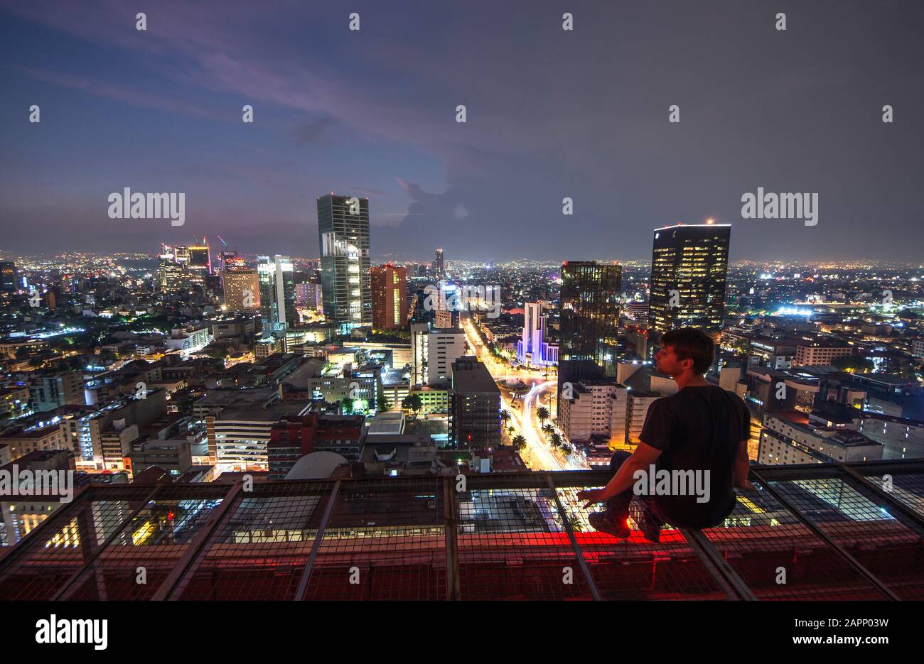 Des hommes assis sur le toit de Mexico avec vue nocturne sur le centre-ville. Ville de Mexico la nuit depuis le sommet Banque D'Images