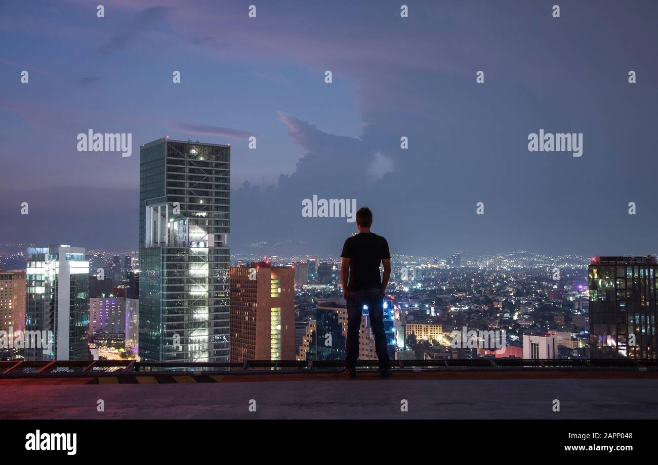 Des hommes se tenant sur le toit de la ville de Mexico avec vue nocturne sur le centre-ville. Ville de Mexico la nuit depuis le sommet Banque D'Images