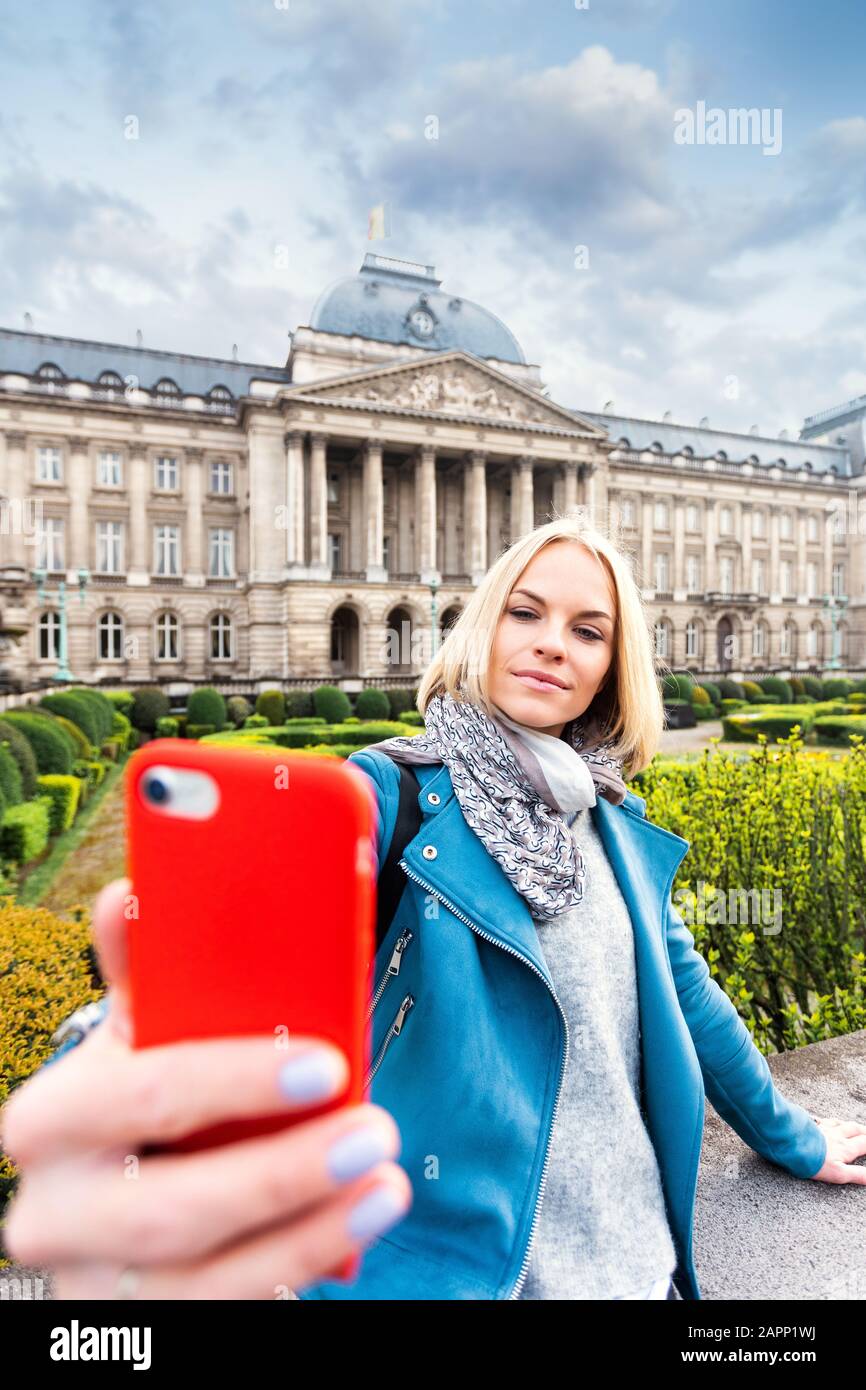 Une jeune femme se tient devant le palais royal de Bruxelles et prend un selfie sur son téléphone, la Belgique Banque D'Images