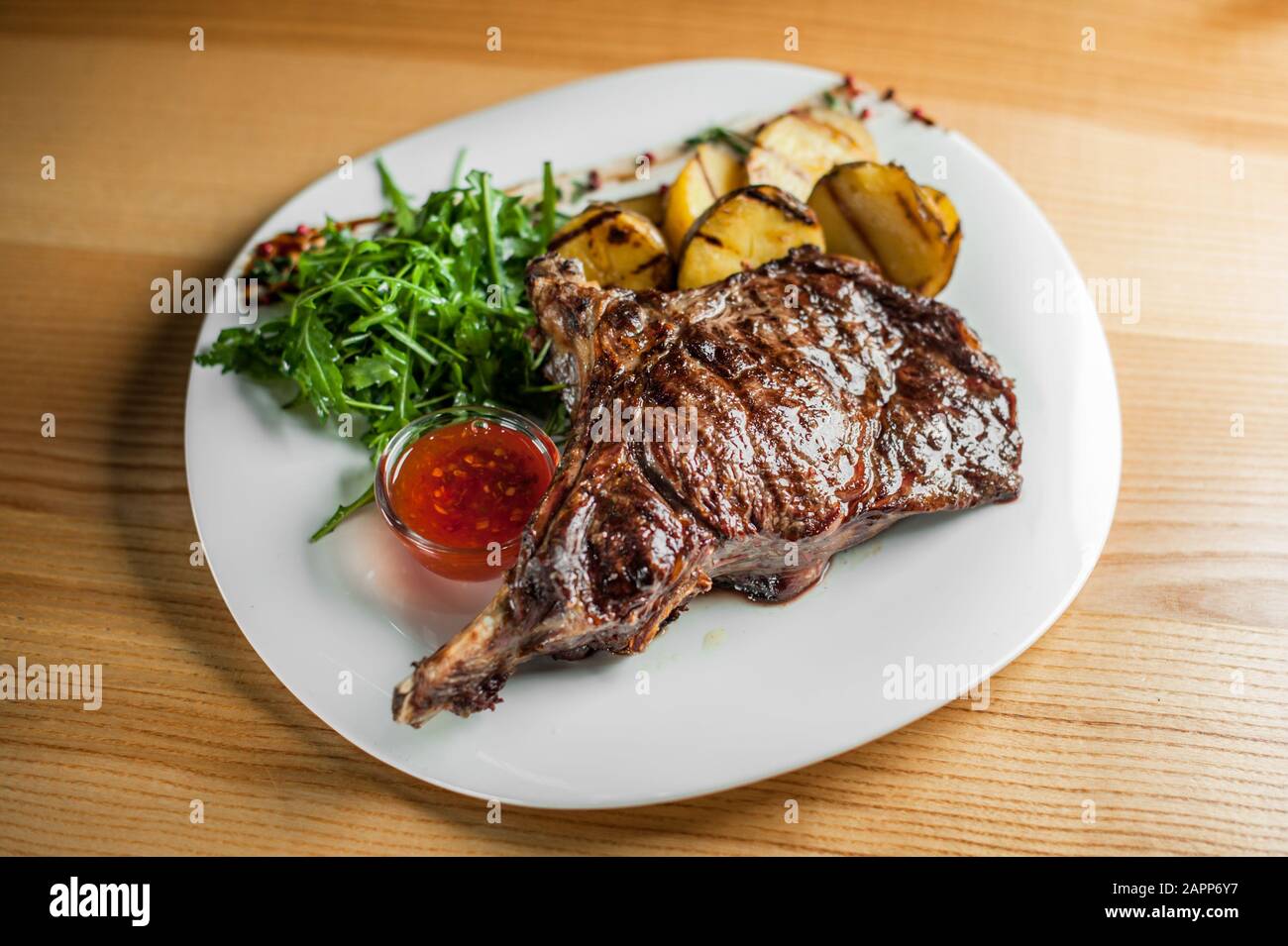 Un steak juteux, délicieux, cuits sur le grill, se trouve avec légumes et sauce sur une assiette blanche. Banque D'Images