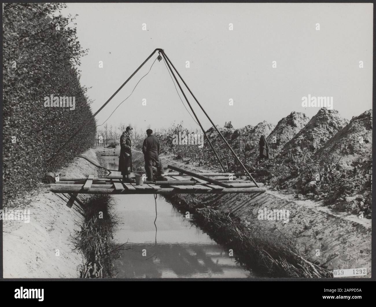 Dans le Jacobapolder d'Anna, près du producteur de fruits de St Philipsland C. Wissen a dû creuser une moat de 100 mètres de long et de 8 mètres de large pour débarrasser ses vergers de sel. Une pompe presse maintenant l'eau à travers de longs tuyaux à travers le sol, après quoi les arbres fruitiers peuvent être vaporisés avec de l'eau douce avec un jet. Le canon à eau a un rayon de 15 mètres et reste au même endroit pendant 12 heures Date: 6 mai 1953 lieu: Anna Jacobapolder, St. Philipsland mots clés: Culture de fruits, réparations, eau, inondation Nom personnel: Wissen C Banque D'Images