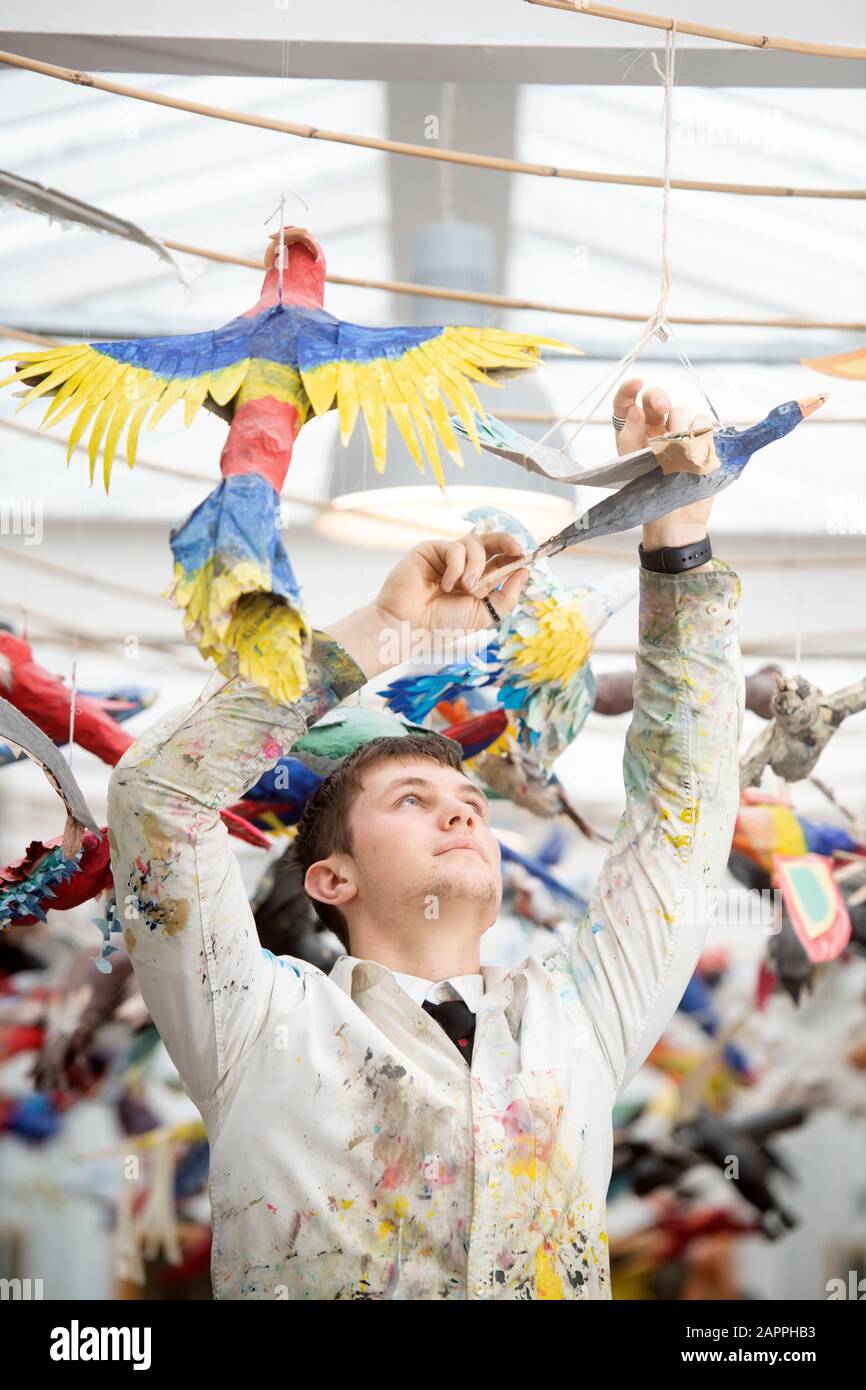 Un étudiant en art suspend les oiseaux en papier dans une école secondaire, au Royaume-Uni Banque D'Images