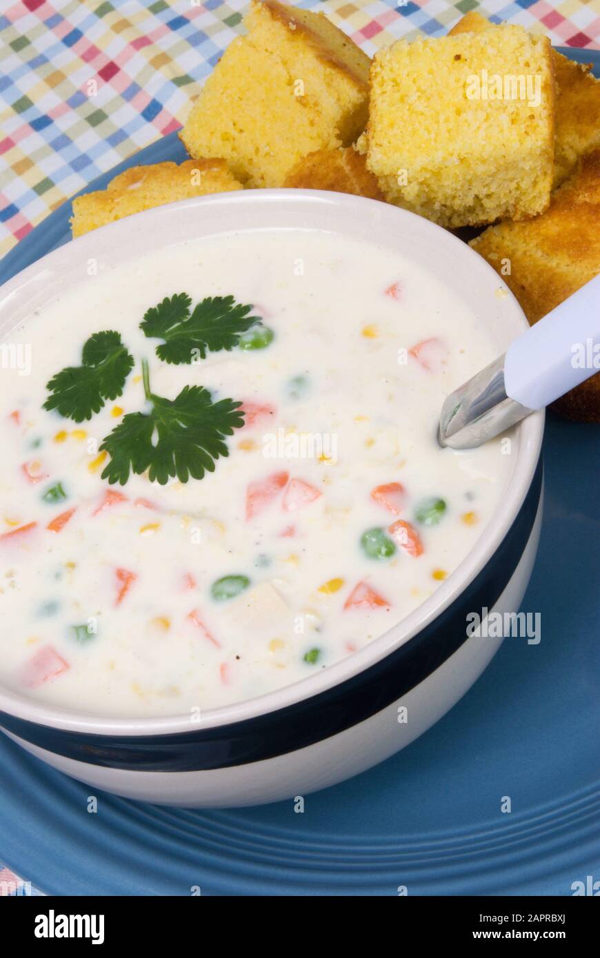 Un bol de soupe de chaudrée maison saupoudrée de persil italien plat sur le dessus et servi avec du pain de maïs jaune chaud frais. Banque D'Images