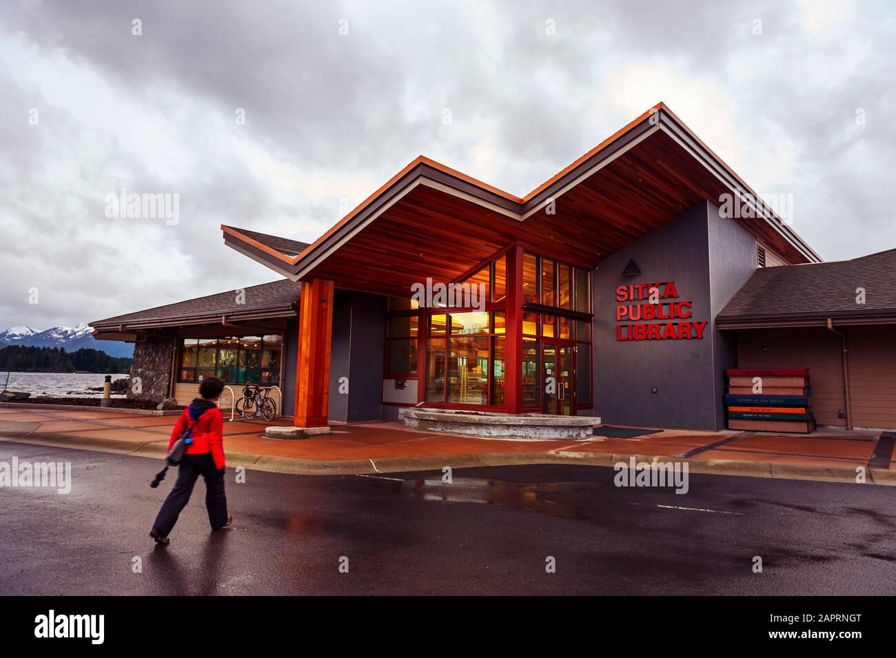 Jeune femme marchant vers la bibliothèque publique de Sitka par un jour pluvieux à Sitka, Alaska, États-Unis. Banque D'Images