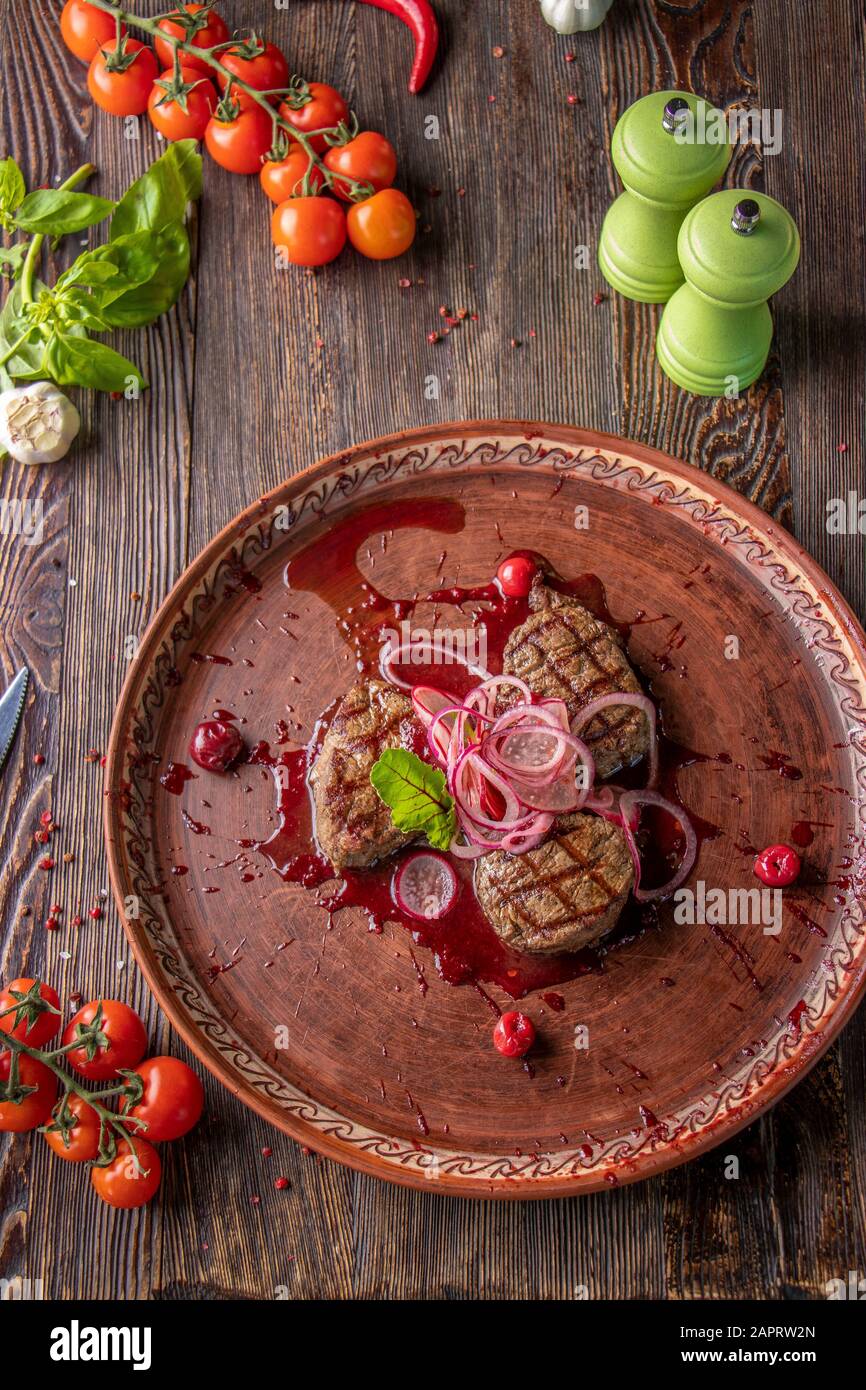 Médaillons de veau à la sauce cerise, servis avec des oignons et des radis marinés, un plat gastronomique, gros plan, vue de dessus Banque D'Images