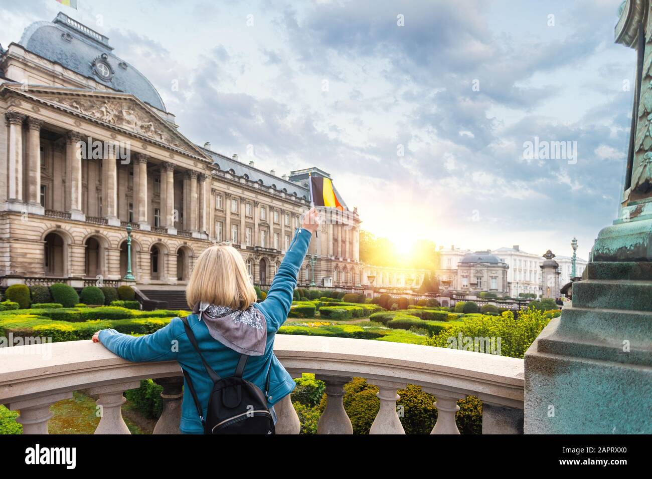 Femme touriste dans des vêtements décontractés se tient avec son dos à la caméra et agitant le drapeau de la Belgique contre le fond du Palais Royal à Bruxelles Banque D'Images