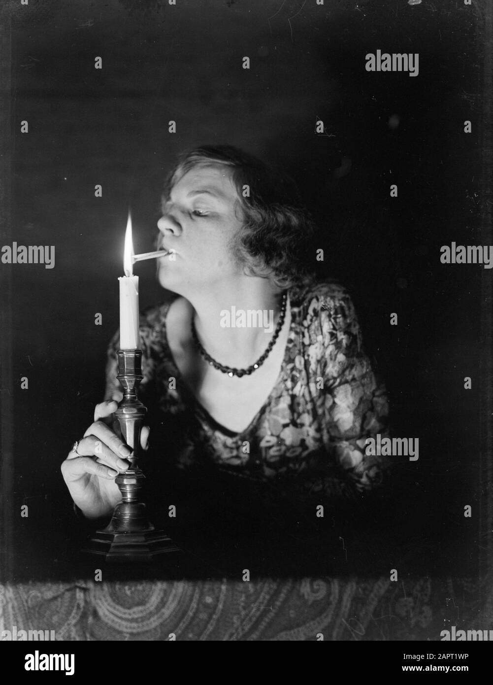 Publicité Photographie une femme allume une cigarette sur une bougie Date : 1932 mots clés : tabagisme, cigarettes, femmes Banque D'Images