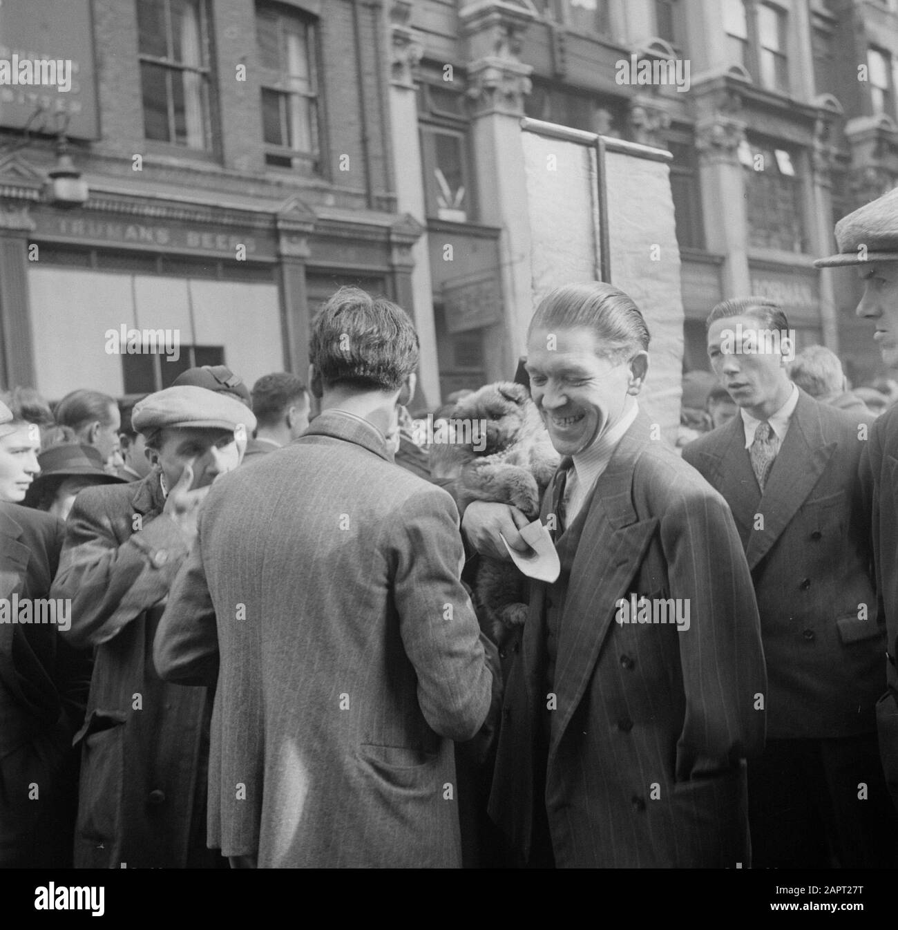 Marché à Petticoat Lane, Londres guerre À Un armée en capacité porter vient d'acheter chien sur bras Date: 1947 lieu: Angleterre, Londres mots clés: Handicapés, chiens, marchés Banque D'Images