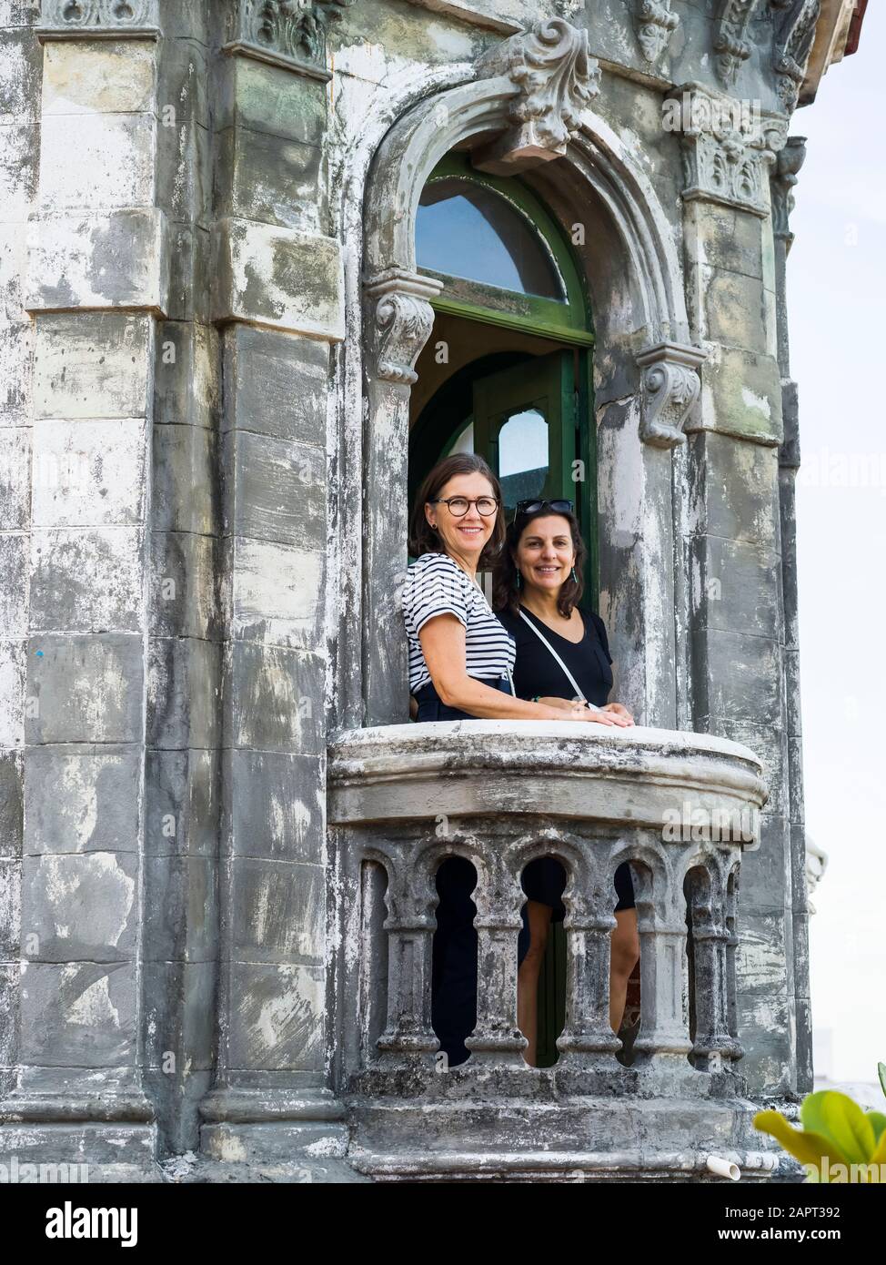 Deux femmes se tiennent sur le balcon d'un ancien bâtiment qui donne sur la caméra, la Havane, Cuba Banque D'Images