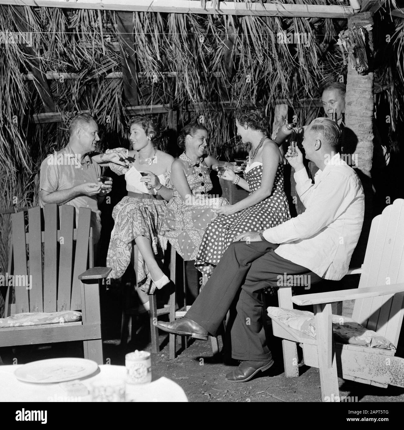 Antilles néerlandaises et Suriname au moment de la visite royale de la Reine Juliana et du Prince Bernhard en 1955 Compagnie du Parti dans une hutte Annotation: Au premier plan deux chaises Adirondack Date: Octobre 1955 lieu: Curaçao mots clés: Parti, femmes Banque D'Images