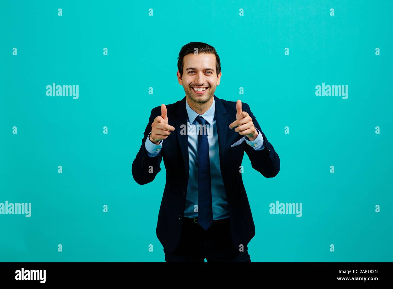 Portrait d'un jeune entrepreneur homme d'affaires souriant, pointant vers l'appareil photo avec index, attitude positive. Isolé sur fond bleu studio Banque D'Images