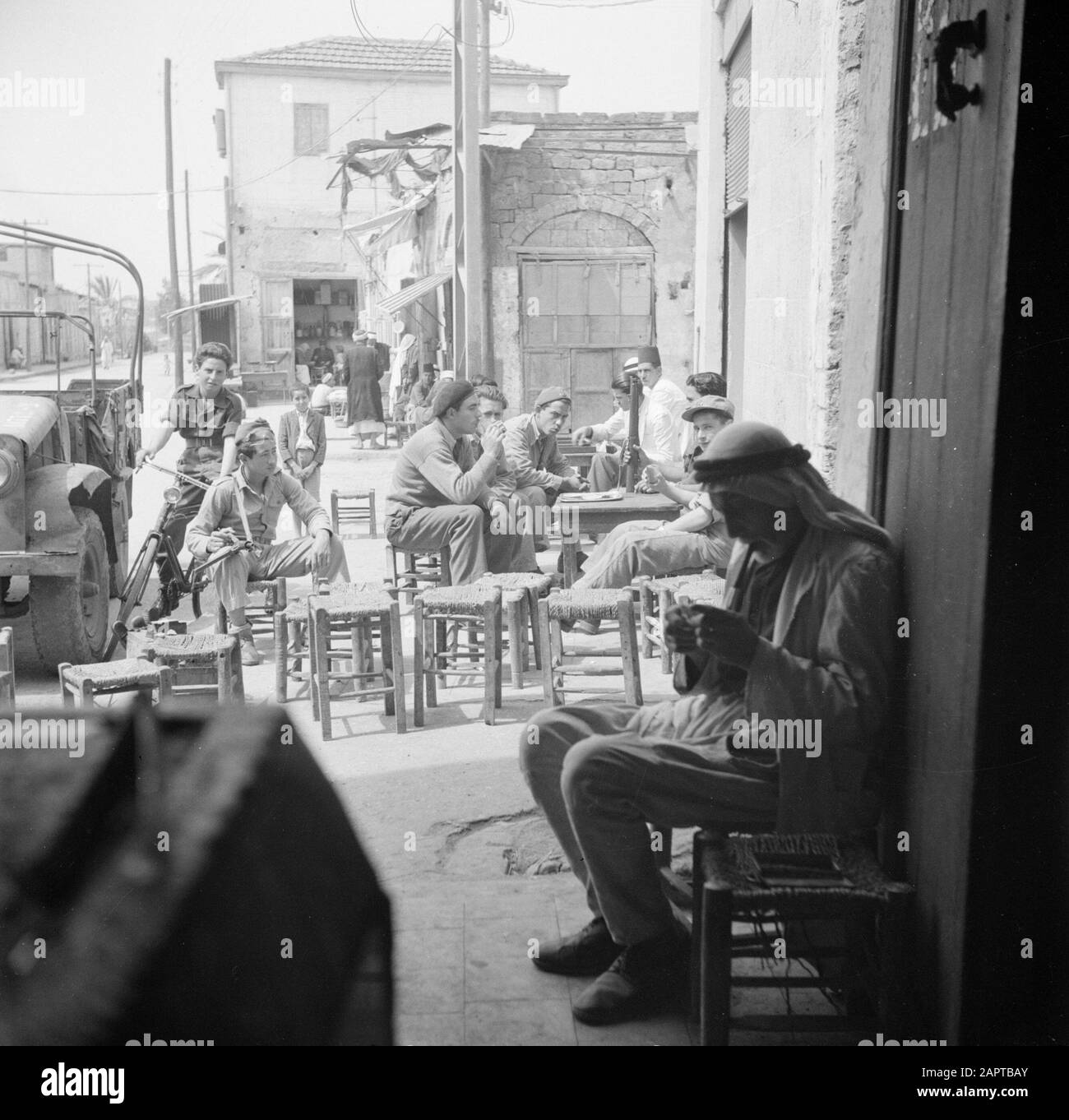 Israël 1948-1949: Majdal (Ashkelon) soldats armés, probablement israéliens, sur une terrasse au milieu des villageois Annotation: Ashkelon est en 1949 après le retrait de l'armée égyptienne reconstruite sur les restes de la ville palestinienne d'Al-Majdal Date: 1948 lieu: Israël, Majdal mots clés: Hommes, soldats, statues de rue, terrasses, armes à feu Banque D'Images