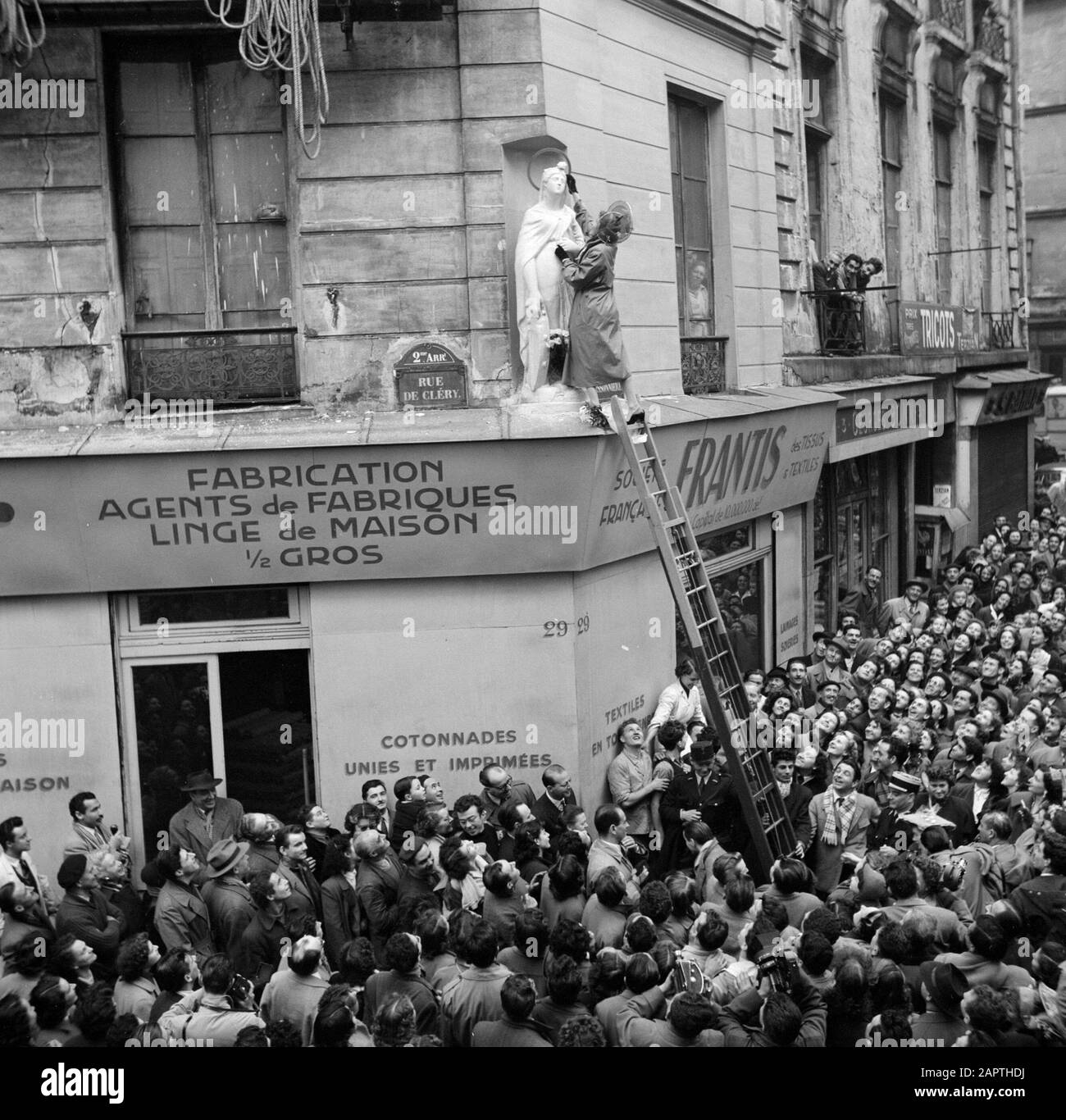 Fête de Sainte Cathédrale à Paris, vacances des maisons de mode françaises le 25 novembre La statue de Sainte Cathédrale à la façade d'un magasin de la rue de Cléry est décorée de fleurs d'annotation : À Paris, la fête de Sainte Cathérine est célébrée par des filles qui sont encore non mariées à l'âge de 25 ans, travaillant dans l'industrie de la mode. Sainte Cathédrale est leur condescendance Date: {1950-1955} lieu: France, Paris mots clés: Vacances, façades, statues de saints, échelles, public, images de rues Banque D'Images