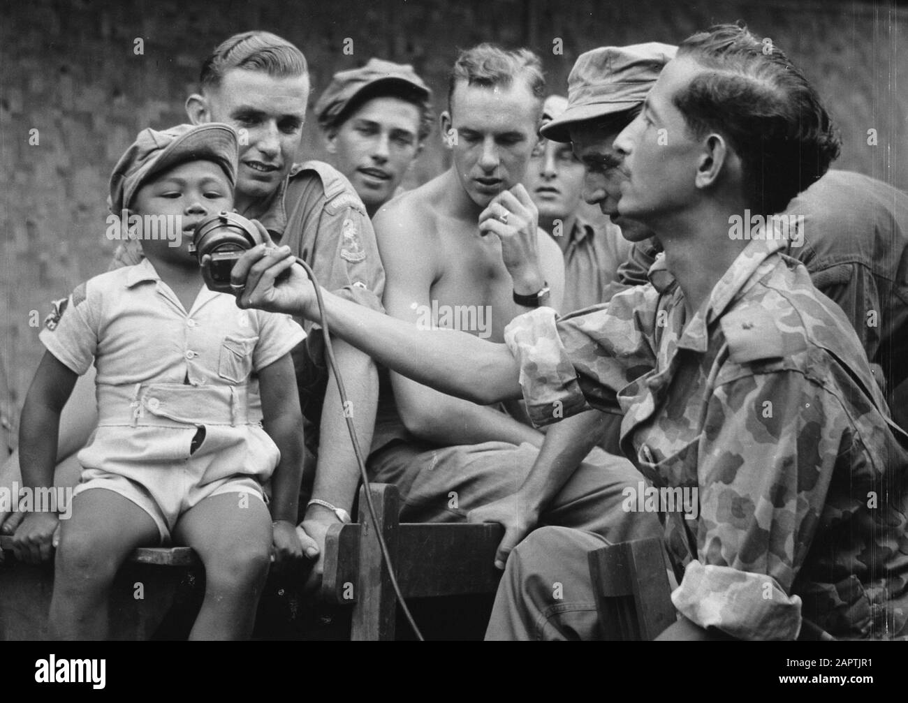 Le petit garçon indonésien (partie armée macotter) peut dire quelque chose par le microphone Annotation: Le lieutenant sur la droite avec le microphone vient en plusieurs images pour. Probablement Reporter Service Army Contacts Date: 1946/01/01 Lieu: Indonésie, Pays-Bas East Indies Banque D'Images