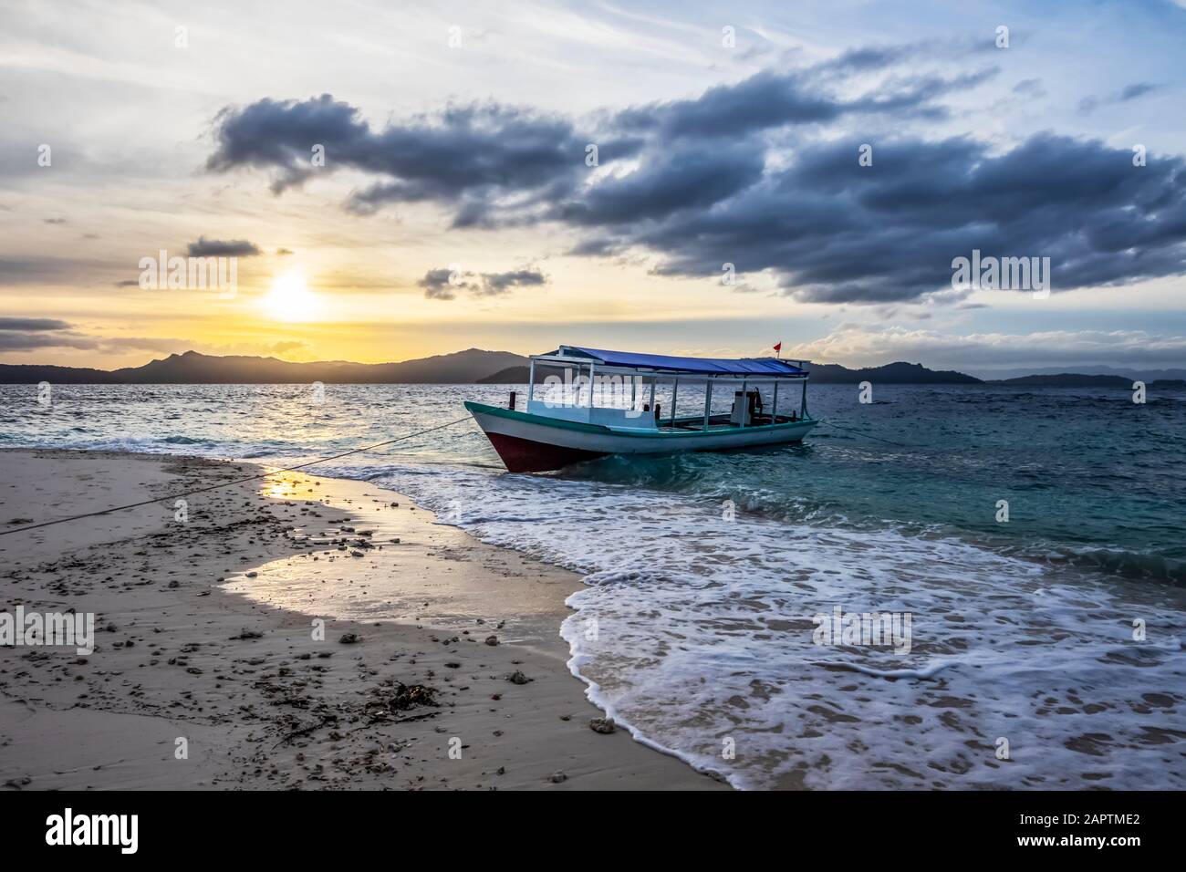 Bateau sur la plage au coucher du soleil, Pulau Kelelawar (île de Bat) ; Papouasie occidentale, Indonésie Banque D'Images