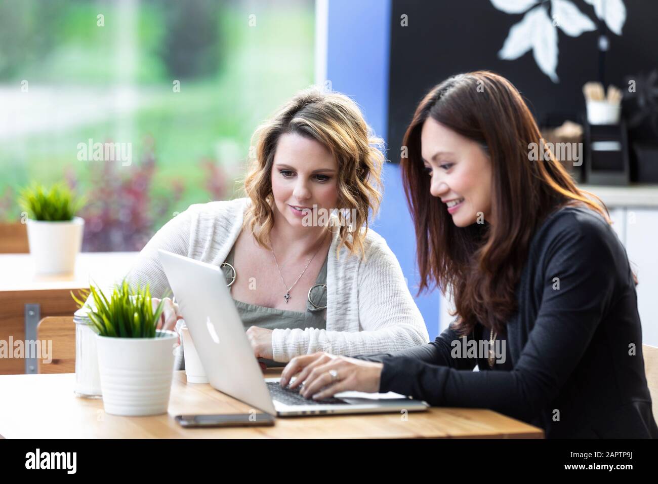 Deux femmes d'affaires professionnelles travaillant ensemble sur un ordinateur dans un café : Edmonton, Alberta, Canada Banque D'Images