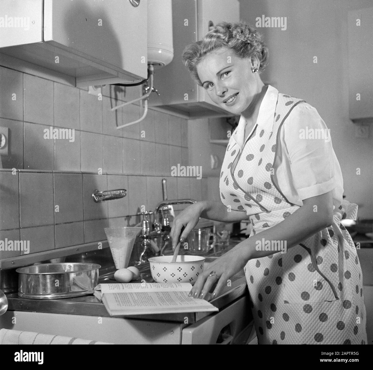 Publicité photographie Housewife dans la cuisine modèle faire un gâteau. Annotation: Photo faite pour la publication "Nous bakken itelemes" écrit par R. Lotgering-Hillebrand et publié par l'éditeur van Holkema & Warendorf Date: 1 juin 1953 mots clés: Cuisines, préparation de nourriture, femmes Banque D'Images