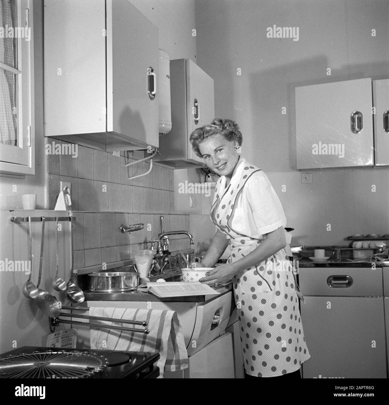Publicité photographie Housewife dans la cuisine modèle faire un gâteau. Annotation: Photo faite pour la publication "Nous bakken itelemes" écrit par R. Lotgering-Hillebrand et publié par l'éditeur van Holkema & Warendorf Date: 1 juin 1953 mots clés: Cuisines, préparation de nourriture, femmes Banque D'Images