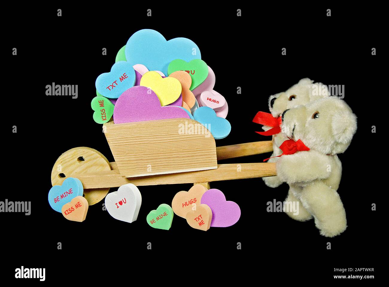 paire d'ours en peluche marron poussant une brouette pleine de coeurs colorés avec message d'amour Banque D'Images