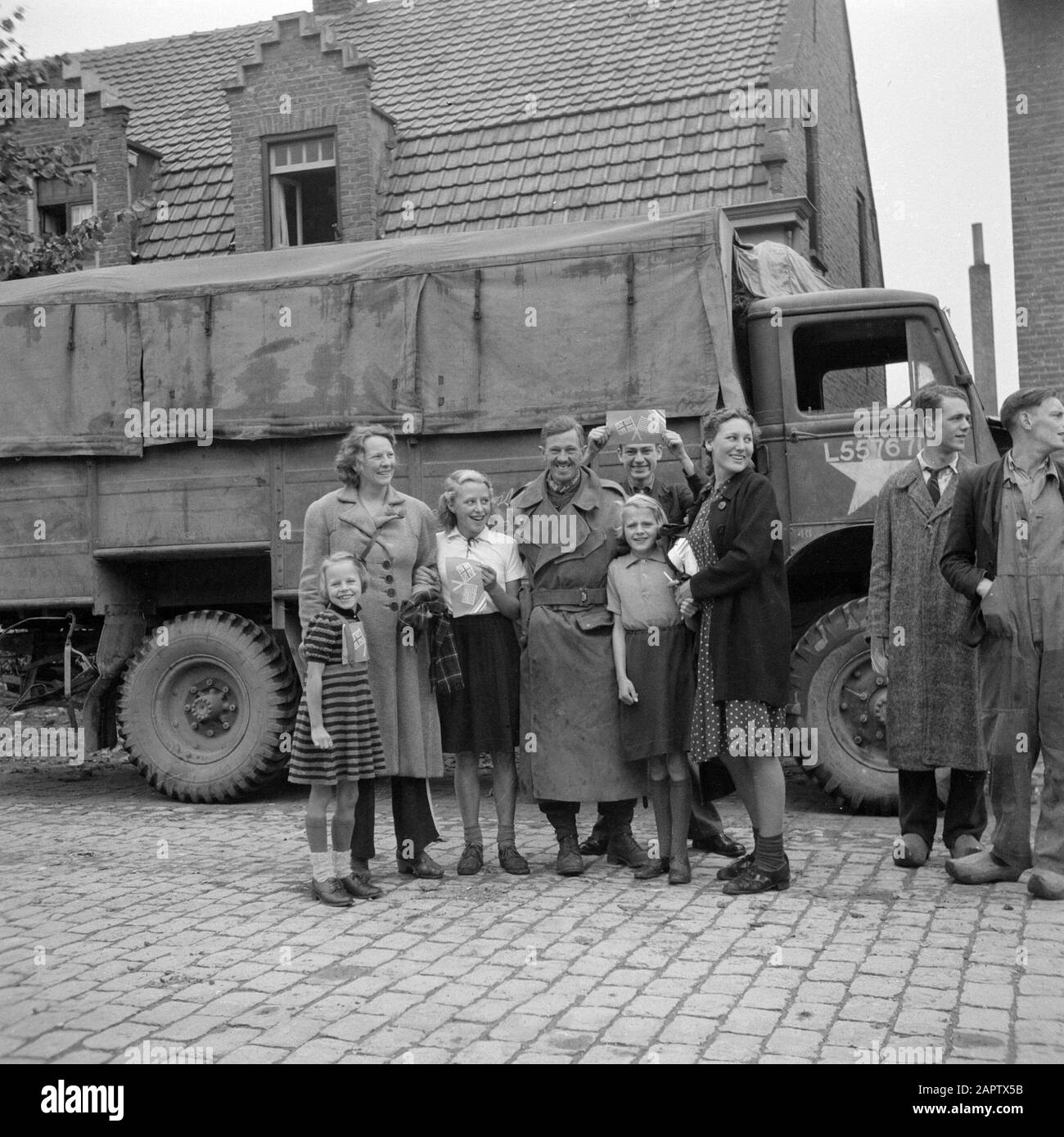 Libération du Brabant du Nord le long du corridor Bergeijk - Valkenswaard - Aalst - Eindhoven résidents d'Aalst posant avec un militaire des gardes irlandais; dans leur main drapeaux britanniques et américains de papier Date: 18 septembre 1944 lieu: Aalst, Noord-Brabant mots clés: Libération, citoyens, villages, portraits de groupe, soldats, drapeaux, camions Banque D'Images