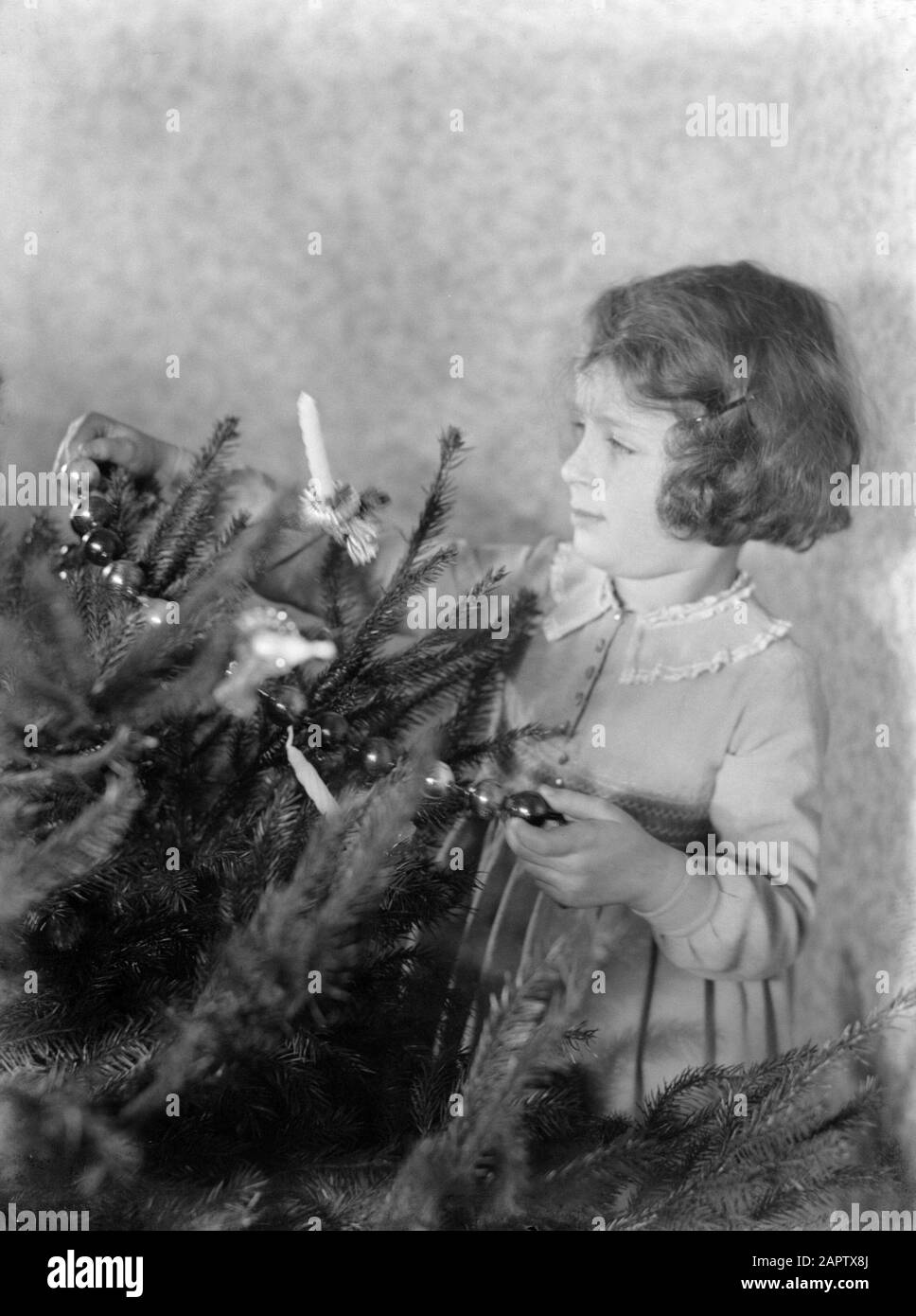 Portraits d'enfants Irmgard porte une guirlande dans un arbre de Noël décoré Date: 1931 mots clés: Bougies, arbres de Noël, décorations de Noël, filles Banque D'Images