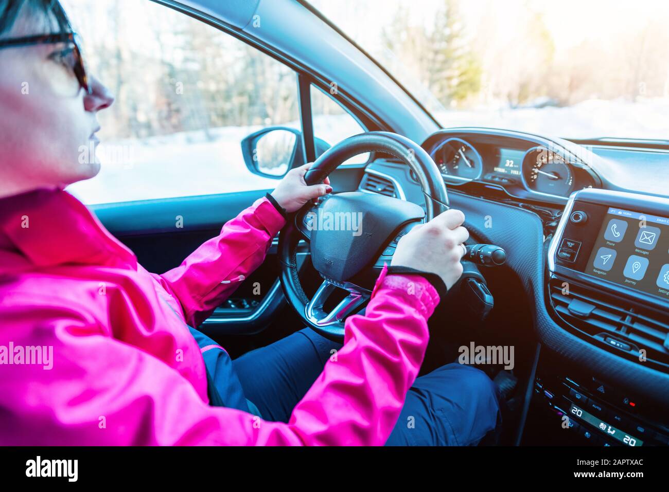 Une jeune fille conduit la voiture en hiver. Le concept de conduite et de déplacement en hiver Banque D'Images