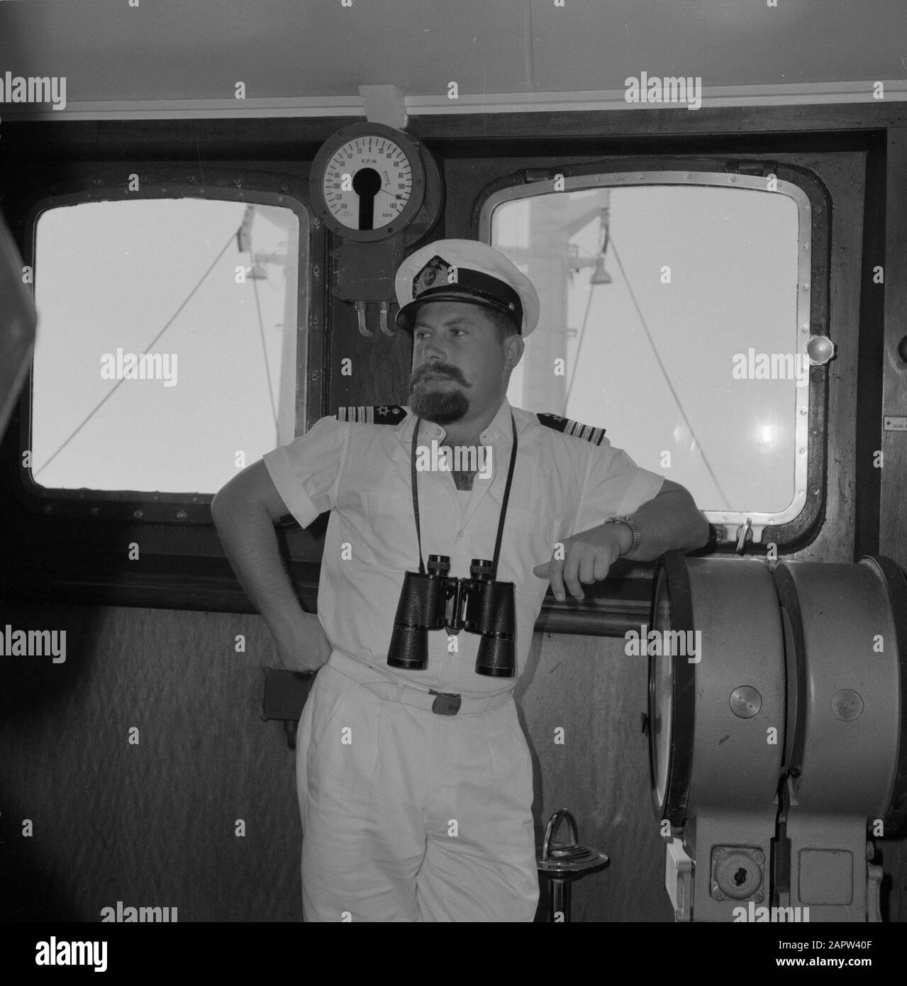 Capitaine en uniforme blanc avec jumelles dans la timonerie debout par la station du navire Date: Non dévêtus lieu: Israël mots clés: Barbes, coiffures, capitaines, uniformes, jumelles, transport maritime Banque D'Images