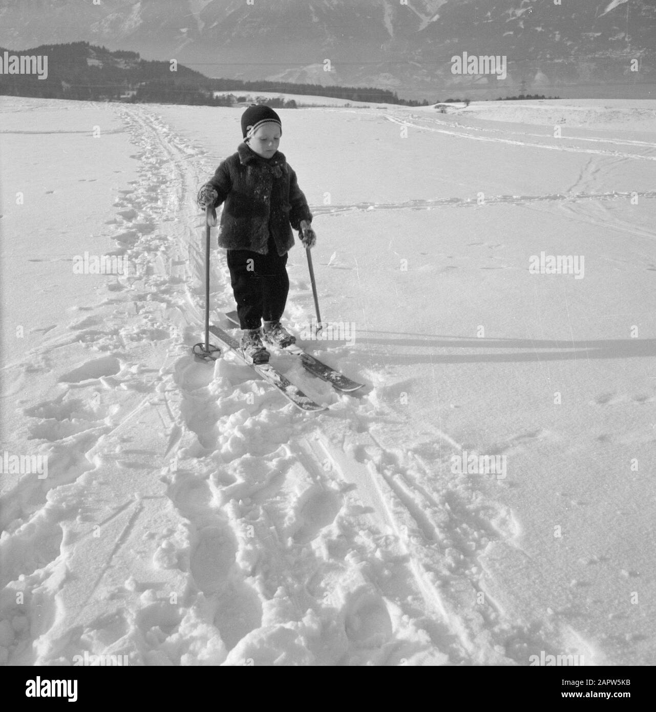 Hiver au Tyrol enfant avec des skis dans la neige avec les montagnes Karwendel en arrière-plan Date: Janvier 1960 lieu: Autriche, Sistrans, Tyrol mots clés: Montagnes, paysages, ski de fond, ski, neige, hiver, sports d'hiver Banque D'Images