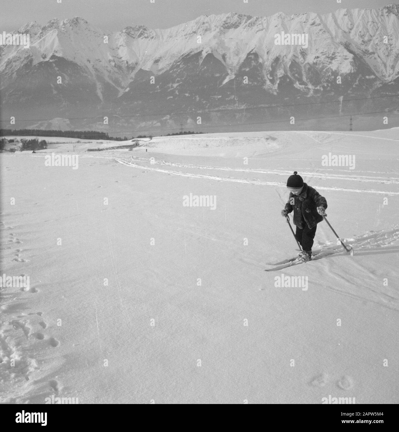 Hiver au Tyrol enfant avec des skis dans la neige avec les montagnes Karwendel en arrière-plan Date: Janvier 1960 lieu: Autriche, Sistrans, Tyrol mots clés: Montagnes, paysages, ski de fond, ski, neige, hiver, sports d'hiver Banque D'Images