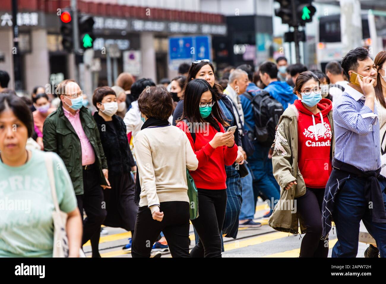 Les personnes qui traversent la route portent des masques chirurgicaux.à la lumière d'une épidémie mortelle de virus en Chine, les citoyens de Hong Kong portaient des masques chirurgicaux dans la crainte de contracter la grippe. Avec les vacances du nouvel an lunaire au coin de la rue, de nombreux citoyens annulant leurs voyages en Chine et progressent avec prudence. Banque D'Images