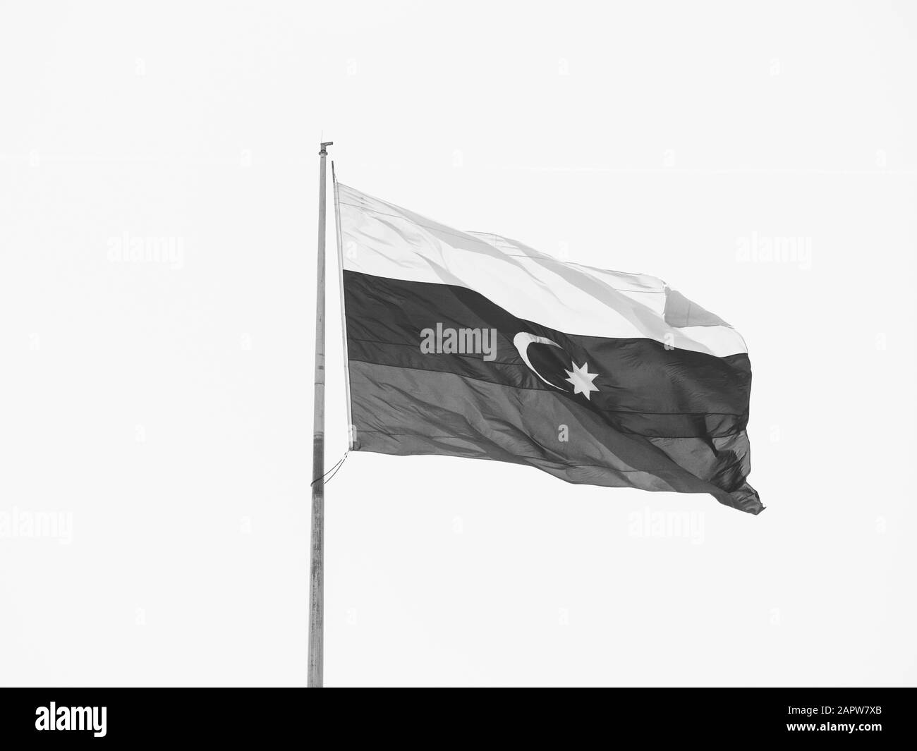 Drapeau national de l'Azerbaïdjan qui coule pendant les vacances nationales contre le ciel bleu clair - image centrale noir et blanc de Bakou Banque D'Images