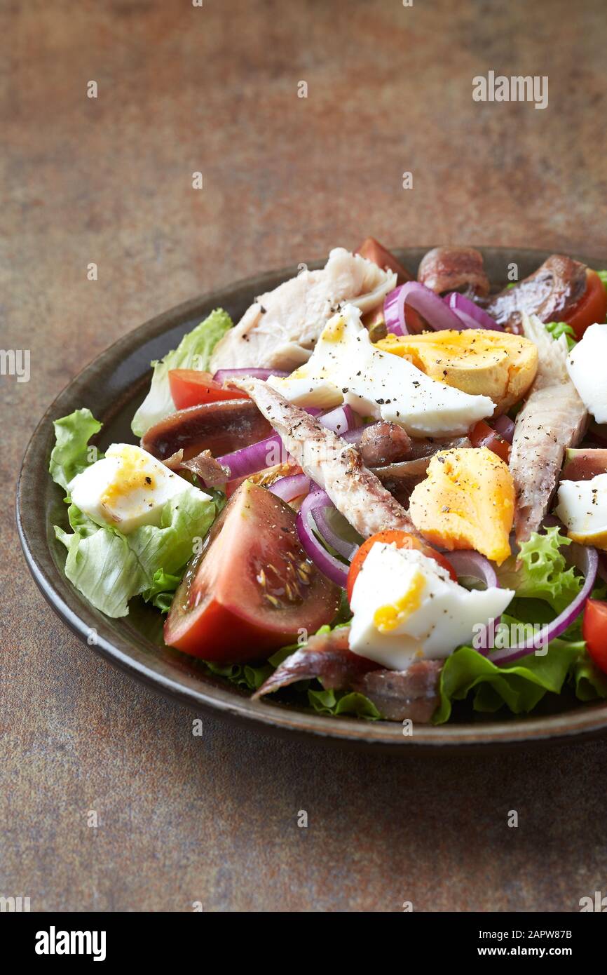 Salade avec œufs durs, tomates, laitue, oignon rouge et maquereau sur fond rustique. Banque D'Images