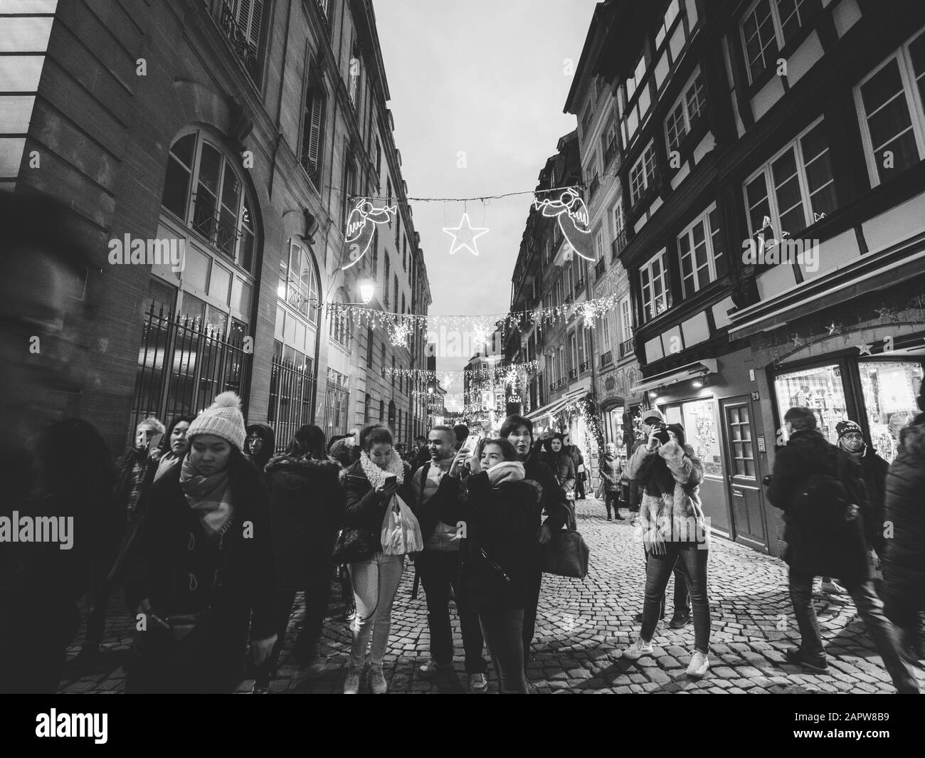 Strasbourg, France - 24 décembre 2018 : vue grand angle noir et blanc d'un grand groupe d'amis touristes marchant en prenant des photos des célèbres décorations de noël de la nouvelle année sur la rue piétonne Banque D'Images