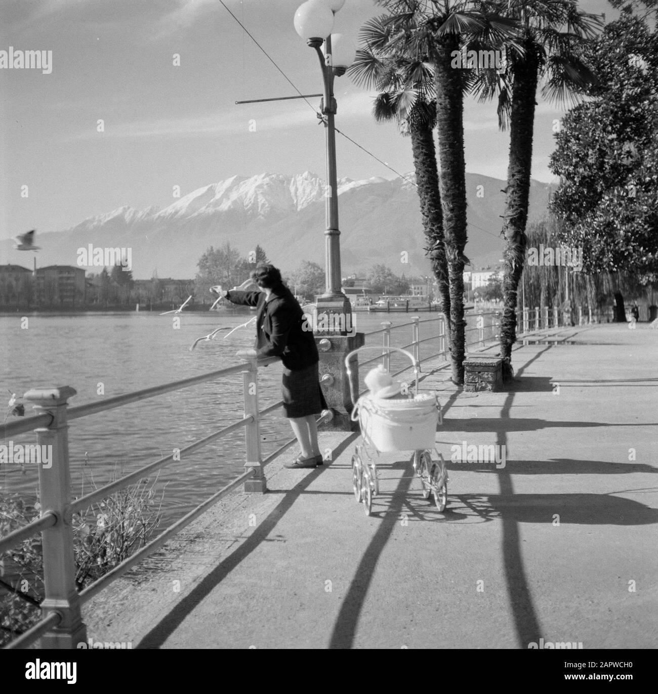 Tour le long du côté suisse du lac majeur Locarno: Boulevard avec enfant et femme alimentant les mouettes Date: Octobre 1961 lieu: Locarno, Suisse mots clés: Montagnes, enfants, paysages, lacs, images de rue, femmes Banque D'Images